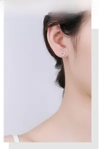 Detail of s925 silver heart stud earrings with cubic zirconia pavé on woman's ear