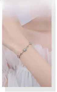 Detail of S925 sterling silver clover bracelet with blue crystals on model wrist