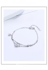 Detail of 925 sterling silver double-layer bracelet with heart crystal and star pendants