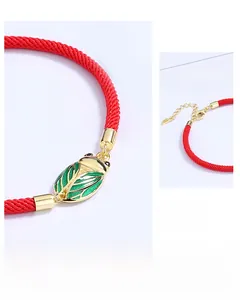 Macro detail of S925 sterling silver golden cicada charm with green enamel on red woven cord