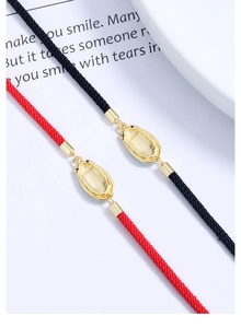 Detailed view of woven red and black cord bracelets with textured gold cicada metal clasp