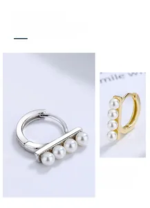 Detailed view of silver and gold hoop earrings featuring four white horizontal pearls