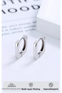 Détail macro de créoles carrées géométriques en argent sterling S925 avec fini poli