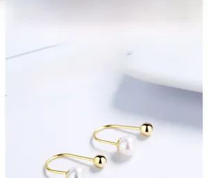Macro shot of U-shaped S925 silver earrings with white pearl and gold metal ball