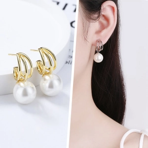 Détail de boucles d'oreilles élégantes en or et argent avec anneaux et perles blanches