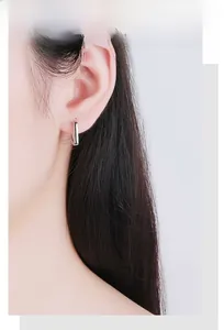 Gros plan de boucles d'oreilles créoles rectangulaires en argent portées par un mannequin