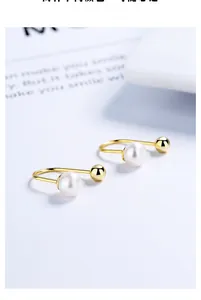Detail shot of U-shaped S925 silver earring with polished gold ball and white freshwater pearl