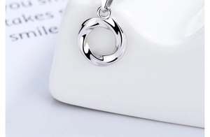 Macro shot of silver Mobius pendant with smooth metallic twist detail on a white stand