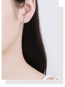 Close-up of a 925 sterling silver feather earring worn on a model's ear cartilage