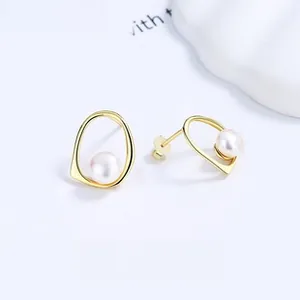 Detail shot of irregular geometric gold earrings featuring a centered round white pearl