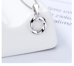 Macro detail of polished 925 sterling silver Mobius ring pendant on delicate chain