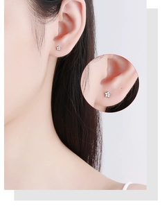 Detailed view of sterling silver star stud earring with white zircon on ear model