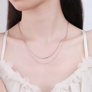 Rose gold layered snake bone chain necklace worn by model over white lace top