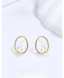 Detailed view of hollow geometric gold earrings with natural white freshwater pearls