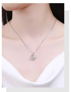 Close-up of a silver swirling pendant necklace with a central gemstone on a female model