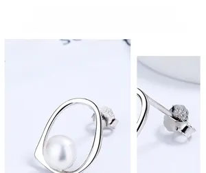 Macro detail of S925 sterling silver stamp and freshwater pearl on geometric earrings