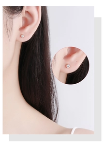 Detail of minimalist rose gold screw back stud earrings with sparkling round zircon