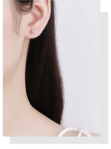 Close-up of small silver starfish stud earring with sparkling stones on model ear