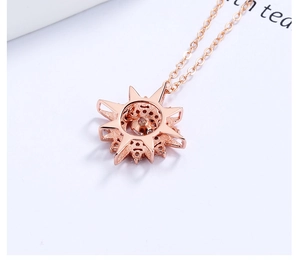 Macro detail of rose gold starburst pendant with crystal center and silver chain
