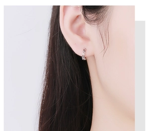 Detail of 925 sterling silver hollow heart hoop earrings worn by a model in soft light
