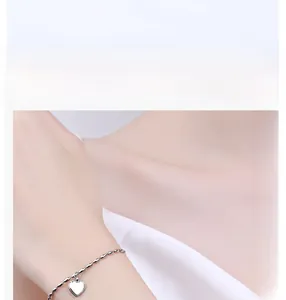 Detail of a minimalist 925 sterling silver beaded bracelet with heart pendant on wrist