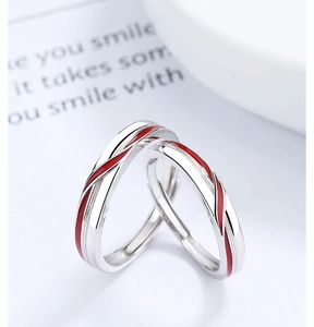Detail of 925 sterling silver couple rings with red enamel line on polished metal surface