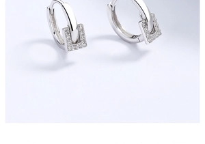 Détail macro de boucles d'oreilles en argent avec pendentifs carrés et zircons pavés