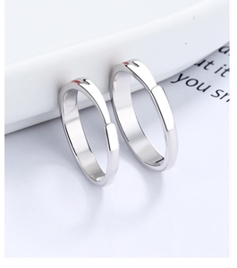 Close-up of a pair of silver rings with red heart detail on a white ceramic plate