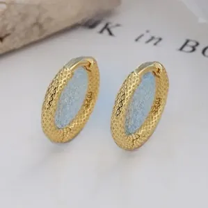 Macro shot of gold twisted hoop earrings showing S925 hallmark and grid texture detail
