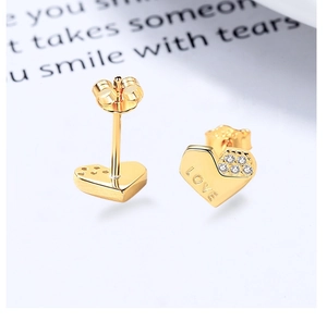 Detail of gold heart earrings featuring LOVE engraving and sparkling zircon stones