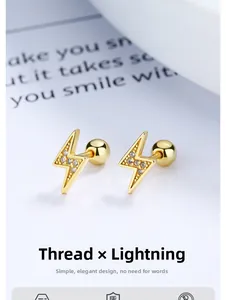 Macro shot of gold lightning bolt earrings with zircons and screw ball backings
