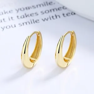 Vue macro de boucles d'oreilles dorées en forme de goutte avec finition polie miroir