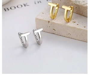Detail of silver and gold T-shaped hoop earrings showing S925 sterling silver stamp