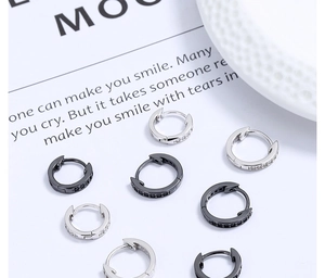 Gros plan de créoles minimalistes en argent et noir avec micro-pavage de zircons