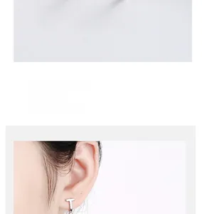Detailed close-up showing T-shaped geometric silver stud earring worn on earlobe