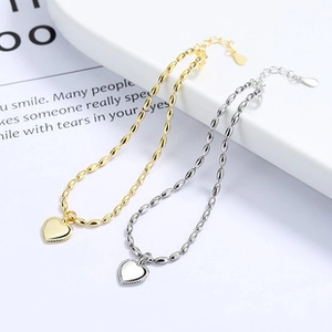 Detailed macro view of heart pendant bracelets in gold and silver finishes with lobster clasp