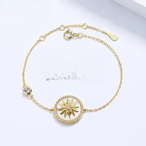 Detail of 18K gold bracelet featuring white mother of pearl compass and star pendant