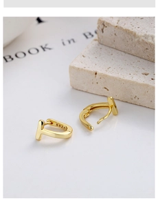 Close-up of golden T-shape silver hoop earrings with S925 hallmark on minimalist stone