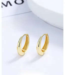 Detailaufnahme glänzender 18K Gold Tropfenohrringe auf einem weißen Display