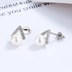 Macro shot of S925 silver triangle stud earrings with pearl and shimmering cubic zirconia