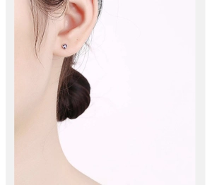Close-up of heart-shaped purple zircon stud earring on earlobe with silver base