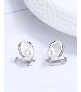 Macro detail of silver heart spiral earrings with freshwater pearl and zircons