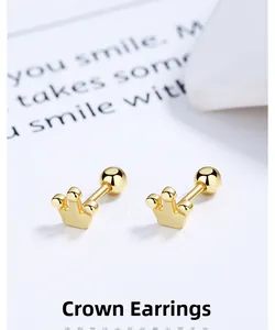 Macro shot of gold crown screw back earrings on minimalist background with card