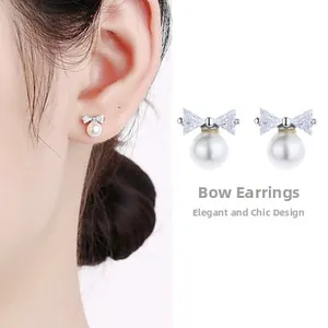 Detailed view of sterling silver bowknot earrings featuring elegant white hanging pearls