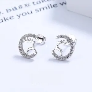 Macro shot of silver deer stud earrings with sparkling cubic zirconia on a sleek moon ring