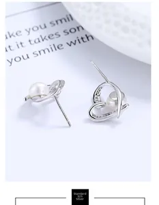 Detail of 925 silver heart pearl earrings with zircon accents on white background