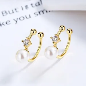 Detail of gold ear cuff with white shell pearl and clear cubic zirconia in U-shape design
