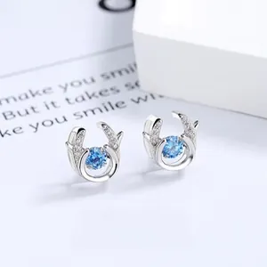 Detail of silver deer antler earrings featuring a dangling blue round gemstone