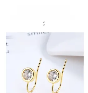 Macro shot of gold-plated silver earrings with bezel-set round white zircon stones