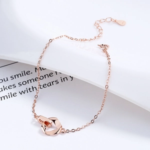 Rose gold Mobius bracelet with interlocking triangle rings on white ceramic background